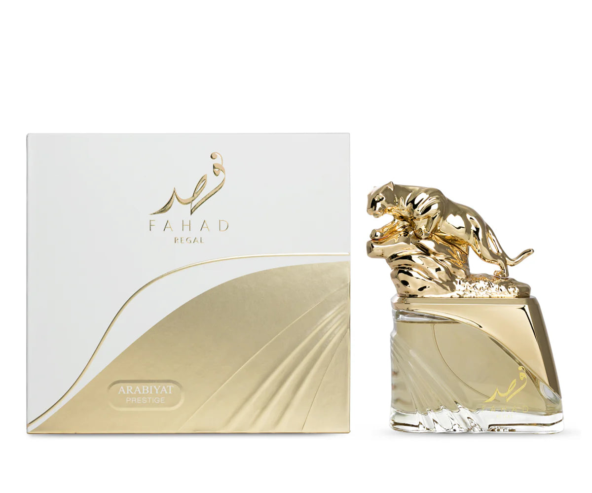 A luxurious unisex ARABIYAT PRESTIGE - FAHAD REGAL 3.4FL.OZ EDP spray features a gold panther-topped bottle, displayed beside an elegant white and gold box with English and Arabic script, offering a captivating ambery floral fragrance.