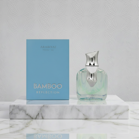 Perfume bottle and packaging with 'Arabiyat Bamboo Reflection' on a marble surface.
