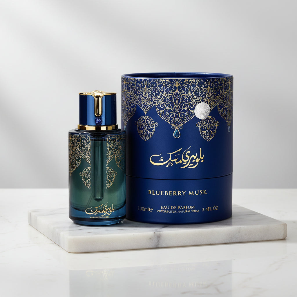 A bottle and cylindrical box of ARABIYAT PRESTIGE - BLUEBERRY MUSK 3.4FL.OZ EDP SPRAY for women and men, both decorated with gold patterns and Arabic calligraphy on a dark blue and green background.